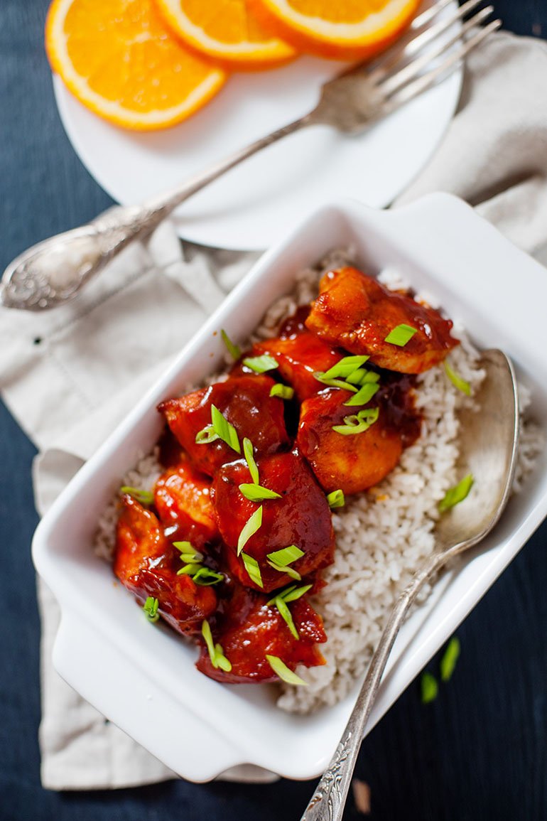 orange chicken recipe served over rice with spoon in dish