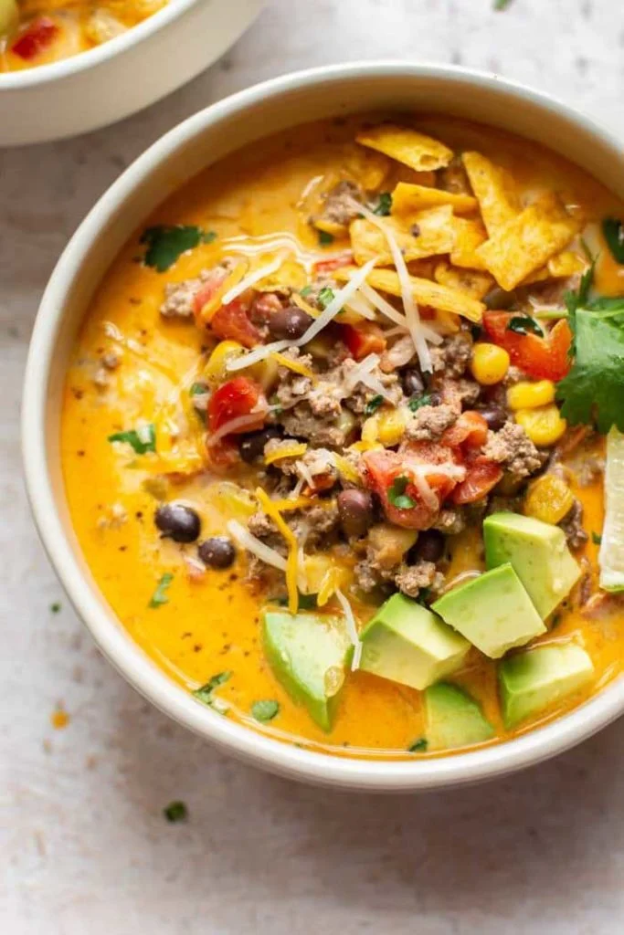 creamy ground beef taco soup topped with avocado and black beans