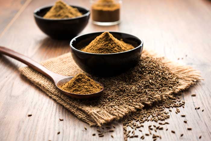 cumin powder in a bowl and wooden spoon
