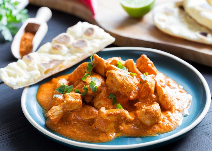 butter chicken served on a blue plate