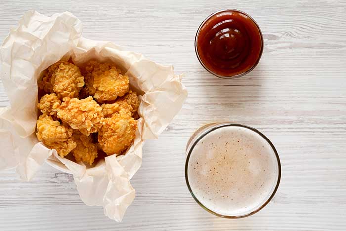 chicken bites in paper box barbecue sauce and glass of beer