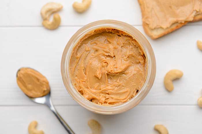 Jar of cashew butter on white wooden background