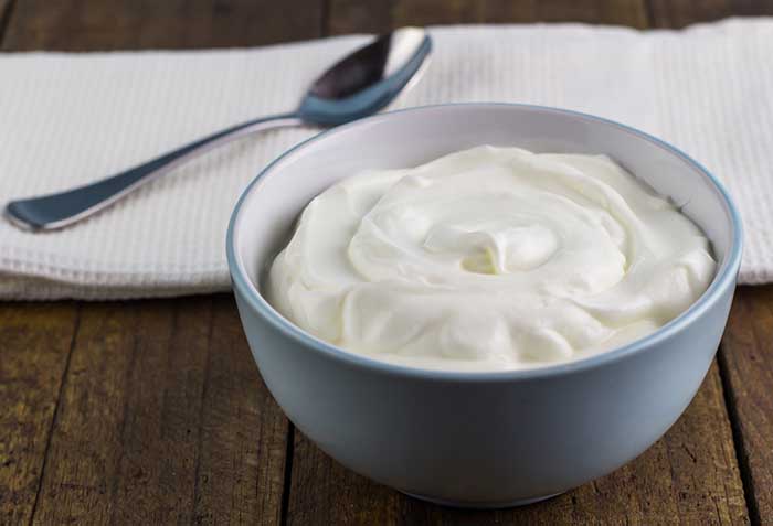 Natural creamy Greek yoghurt on wooden table