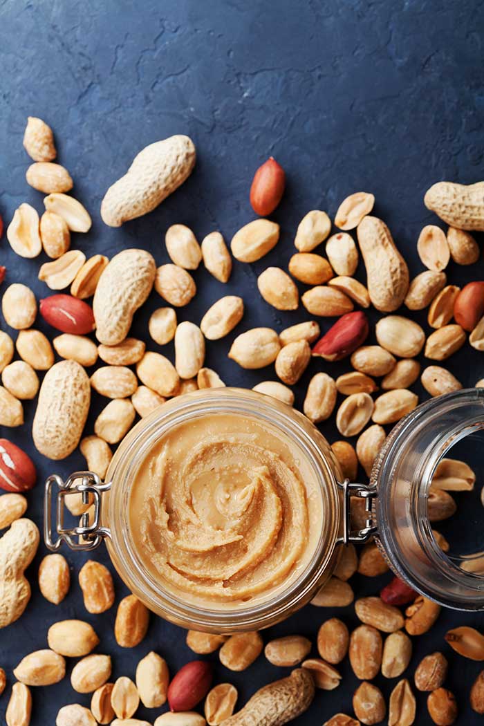 a jar of homemade peanut butter with raw peanuts