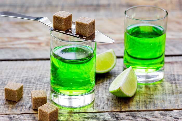 absinthe in glass with lime slices on wooden background