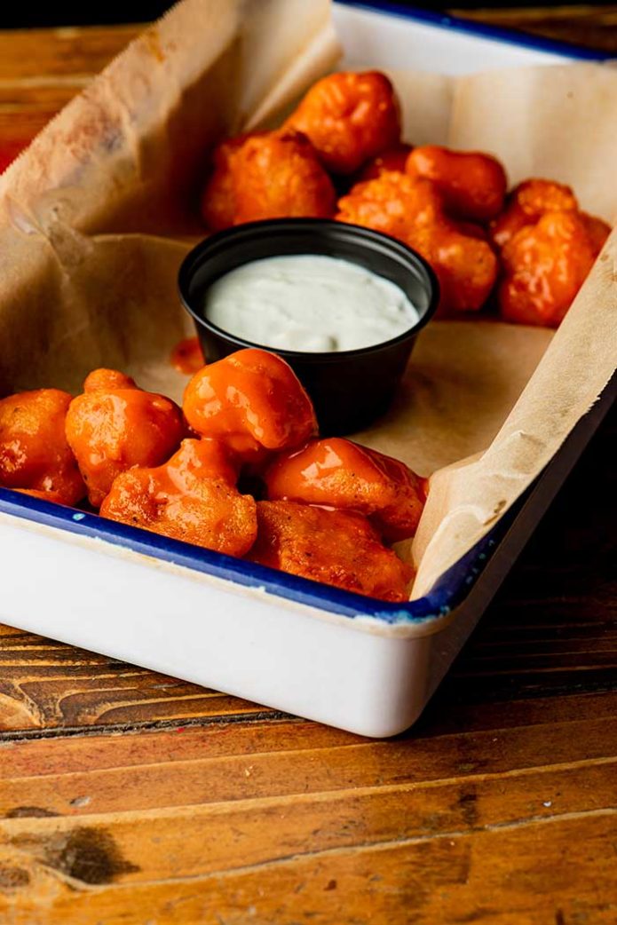 buffalo chicken bites served in brown parchment paper served with blue cheese ranch dipping sauce