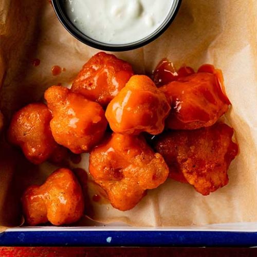 buffalo chicken bites served in brown parchment paper served with blue cheese ranch dipping sauce