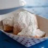 French beignets with powdered sugar on top on blue picnic table