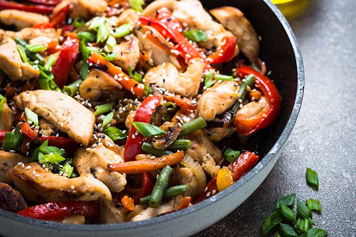 chicken stir fry with vegetables and sesame in the pan