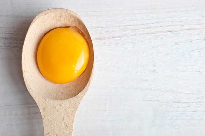 egg yolk in spoon wooden background