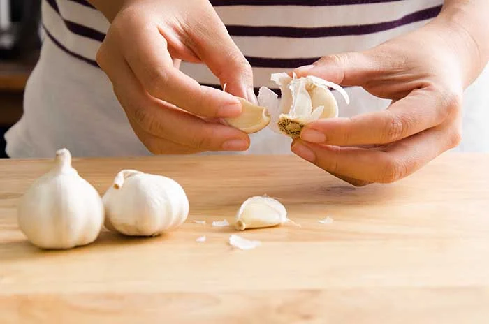 chef peeling garlic for paste recipe