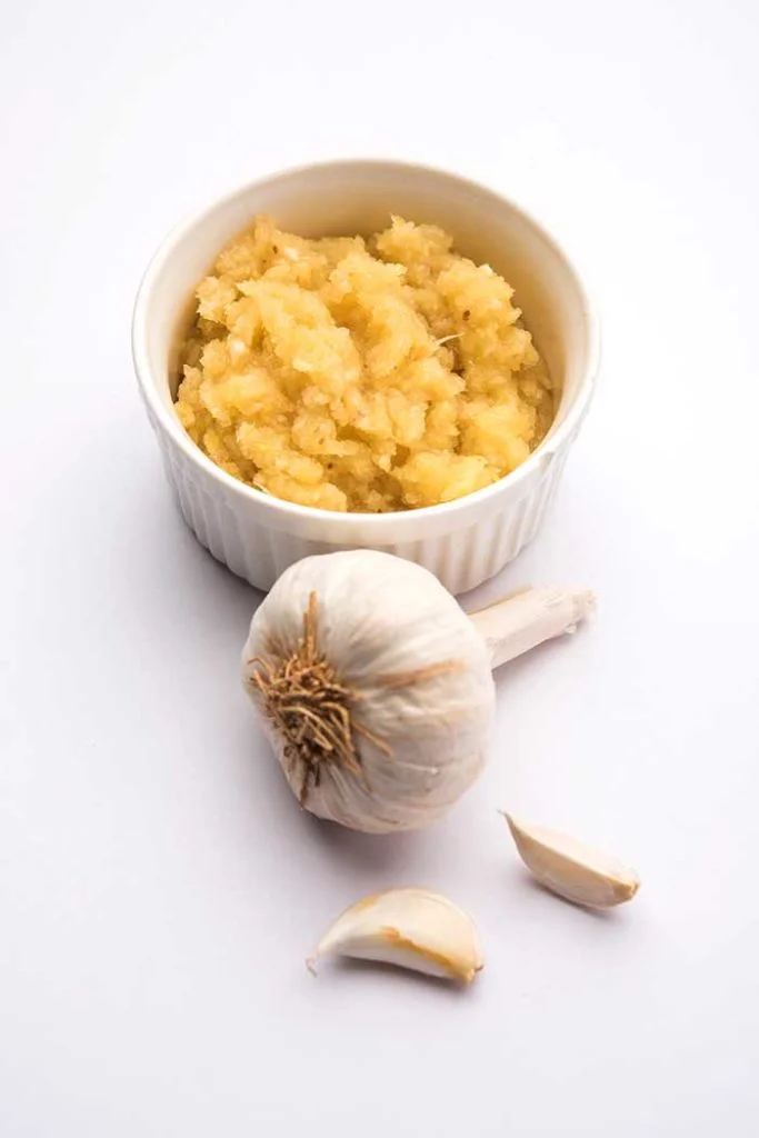 roasted garlic puree in serving bowl with whole garlic bulb