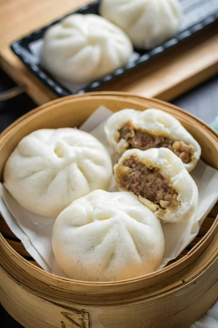 steamed chinese gluten-free bao buns resting in bamboo baozi steamer showing ground pork filling