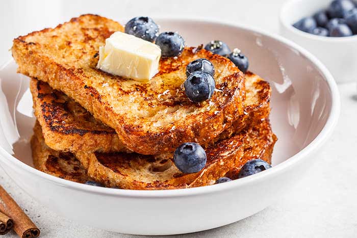 keto french toast with blueberries and low-sugar honey on a white plate