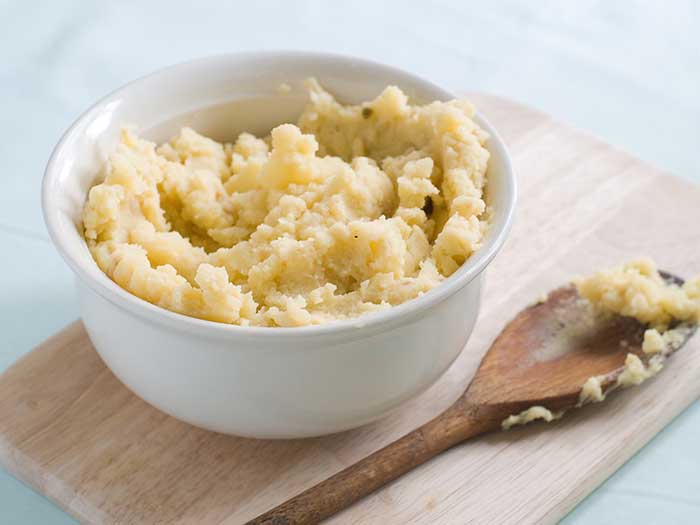 mashed potato with wooden spoon in serving bowl