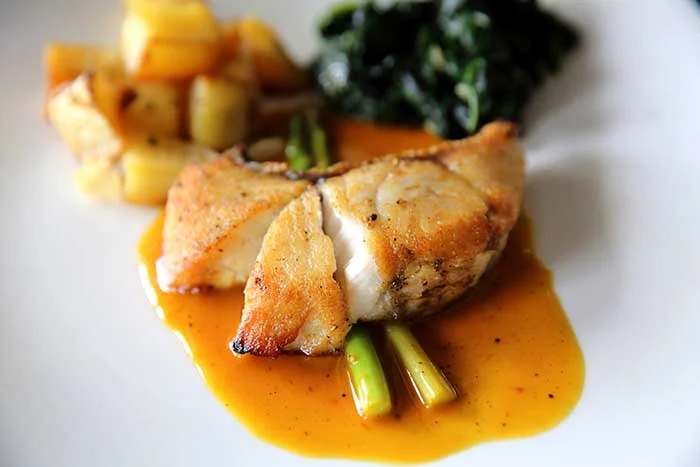 chilean sea bass fillet steak with potatoes and spinach in lemon sauce