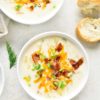 Delicious potato creamy soup with bacon and cheddar cheese in bowl on light stone