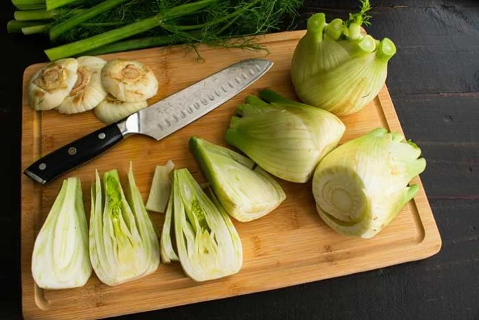 quartering fennel Bulbs on a bamboo cutting board
