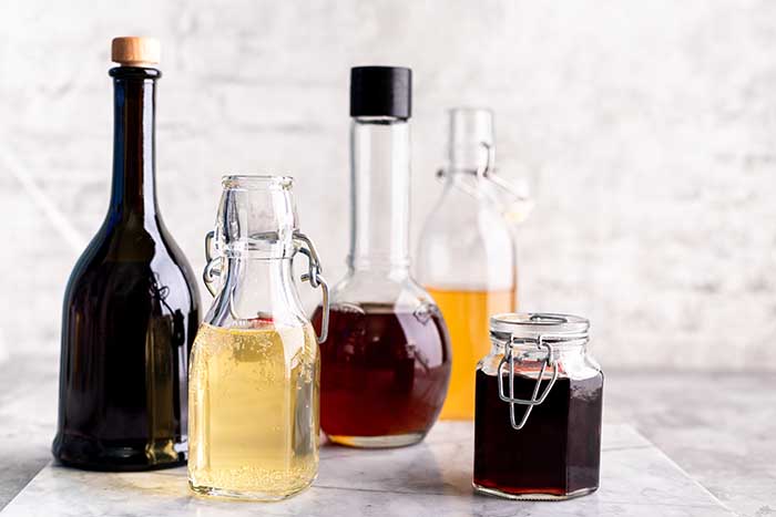 collection of rice vinegar bottles including brown, red, and white rice vinegars