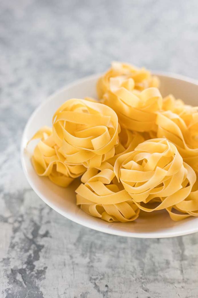 Tagliatelle raw Italian pasta on a light background